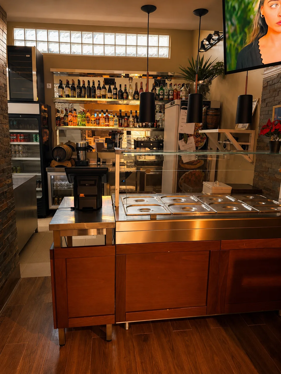 Bar do rés-do-chão com balcão em inox, prateleiras iluminadas de garrafas, máquina de café e frigoríficos de bebidas