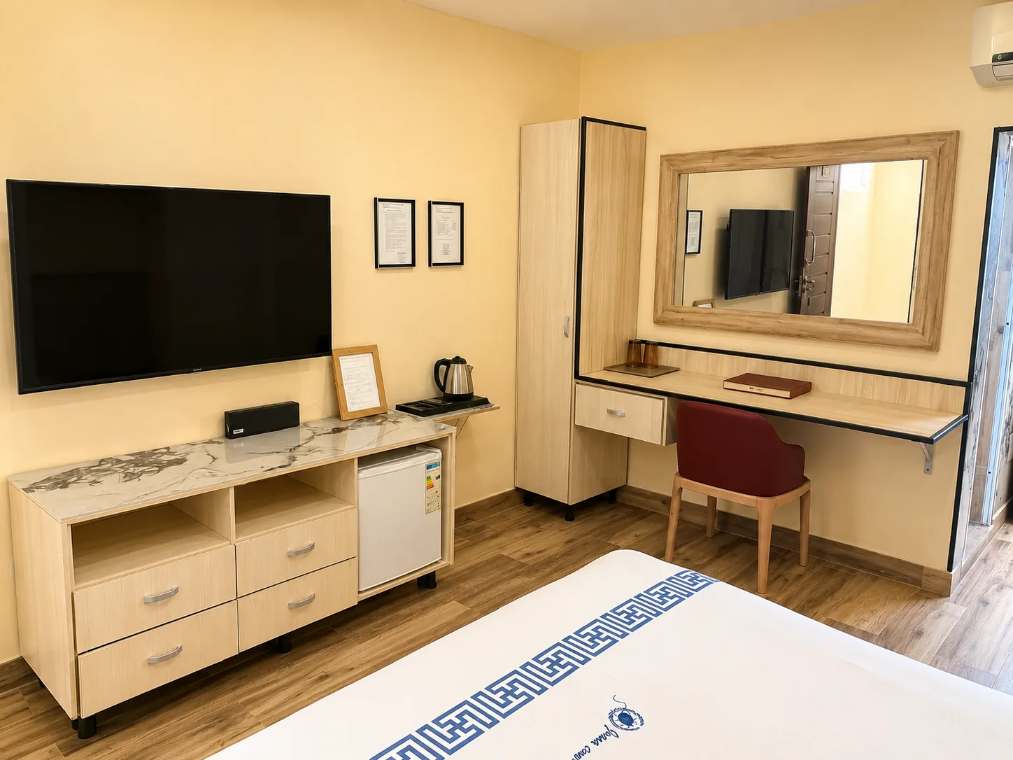 Quarto Solteiro Maior com televisão de parede, cómoda em mármore, frigorífico, roupeiro alto e toucador com espelho e cadeira